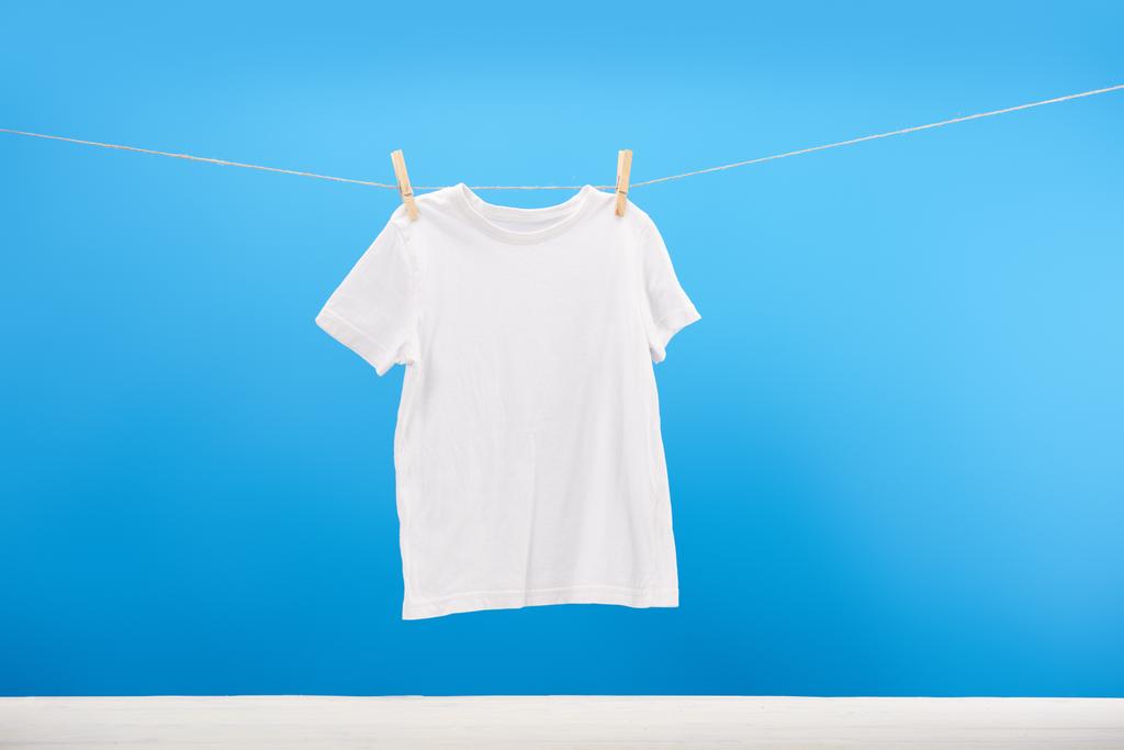 limpo branco t-shirt pendurado no varal em azul
  - Foto, Imagem