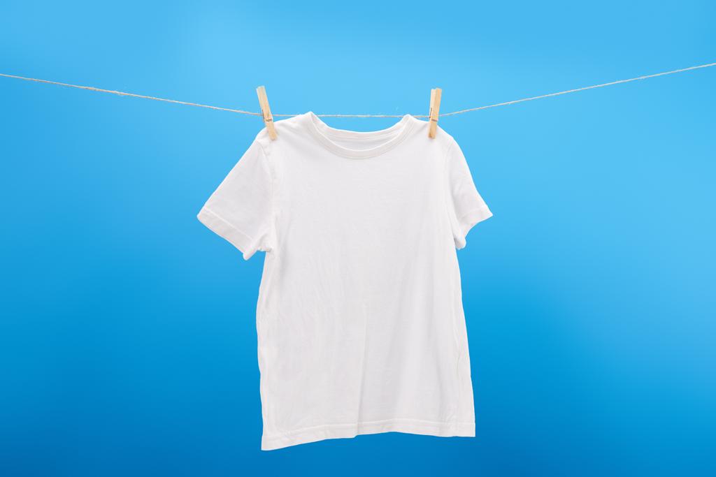 洗濯はさみ青に分離された洗濯物に掛かっている白い t シャツ     - 写真・画像