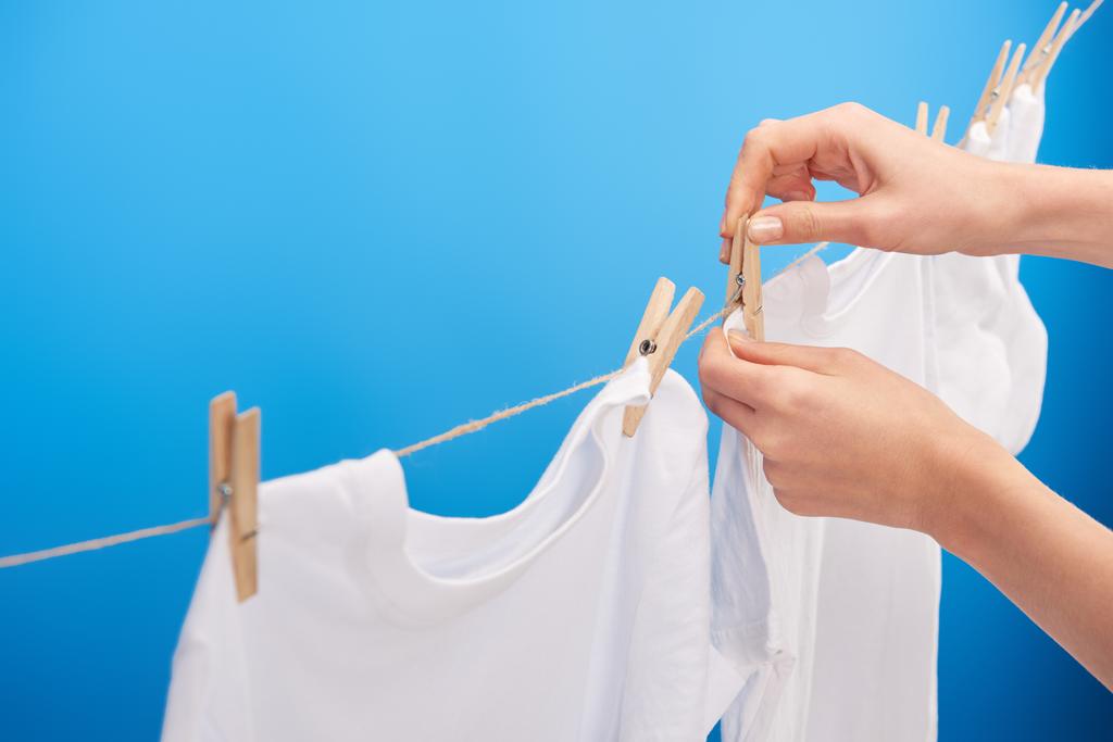 cropped shot of person hanging clean clothes with clothespins on clothesline isolated on blue - Photo, Image