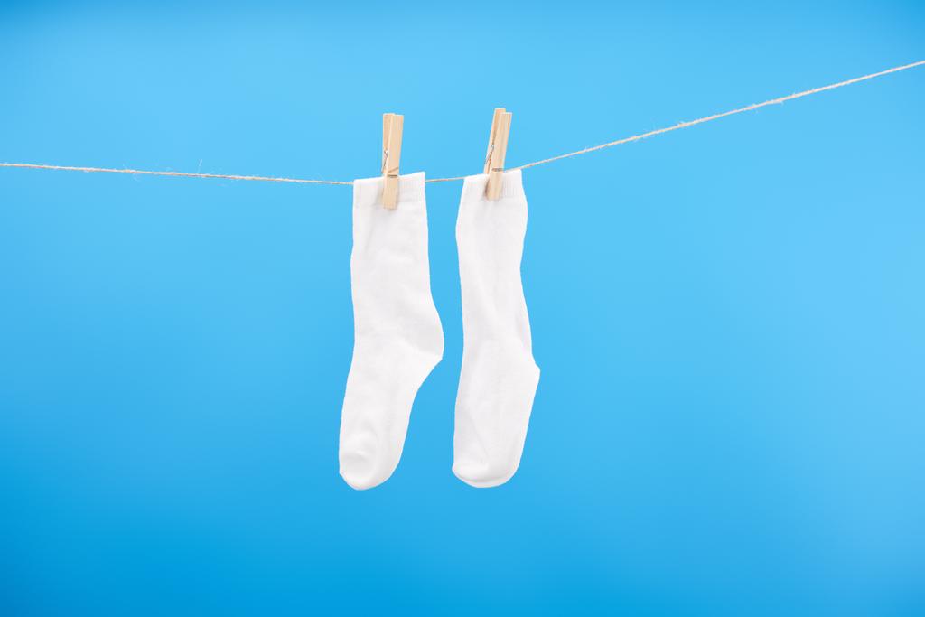 calcetines blancos limpios colgando sobre tendedero aislado sobre fondo azul
 - Foto, imagen
