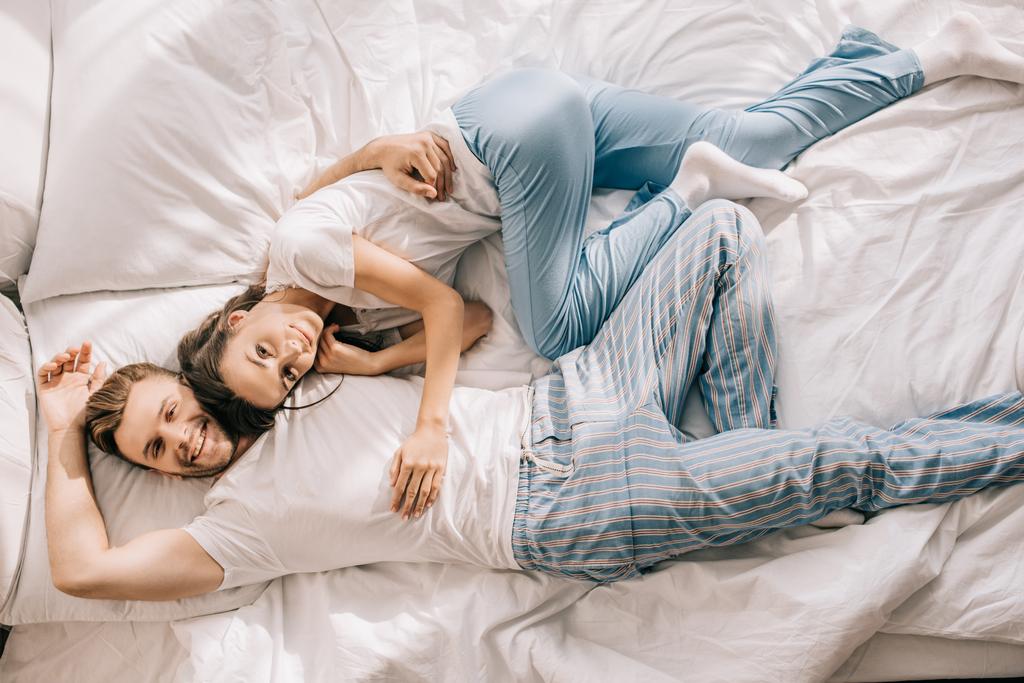 vista superior de la hermosa pareja joven relajarse en la cama por la mañana
 - Foto, Imagen
