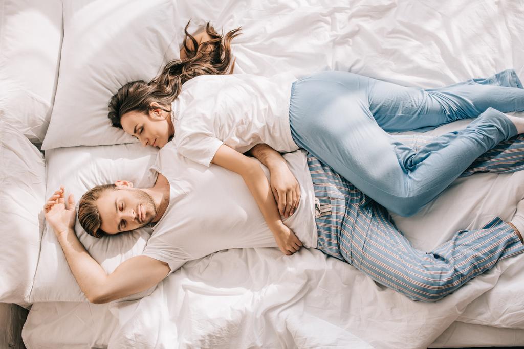 朝のベッドで寝ているパジャマで美しい若いカップルの平面図 - 写真・画像
