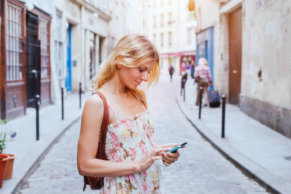 Kobieta za pomocą mobilnych na ulicy, smart phone aplikacji - Zdjęcie, obraz