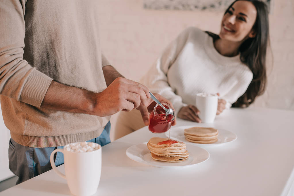 自宅の朝食のパンケーキと若いカップルのショットをトリミング - 写真・画像