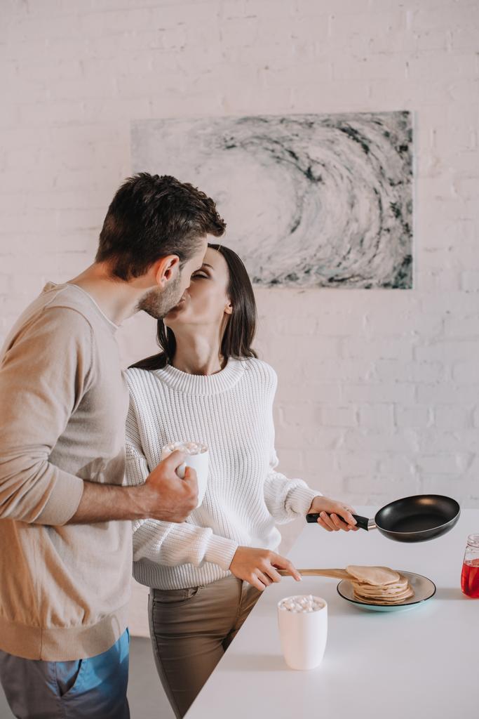 hermosa joven pareja haciendo desayuno juntos y besándose
 - Foto, imagen