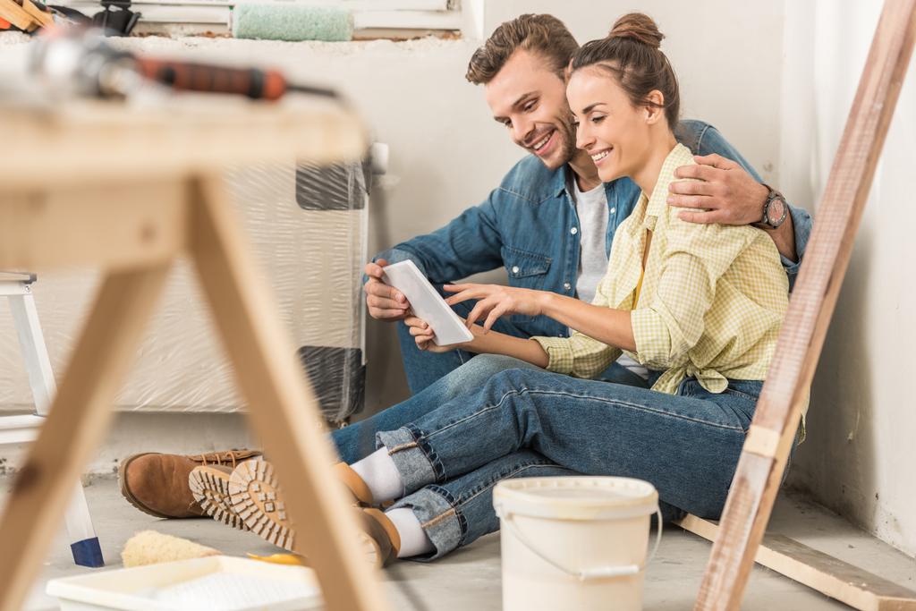 heureux jeune couple en utilisant tablette numérique lors de la rénovation dans la maison neuve
  - Photo, image