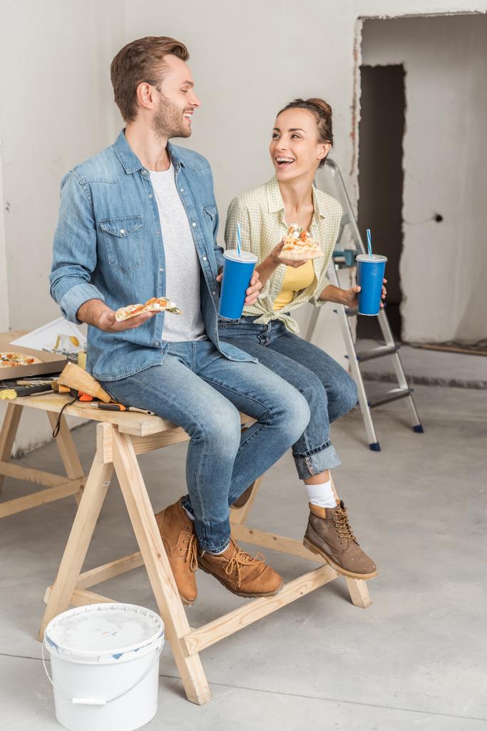 heureux jeune couple tenant des tasses de pizza et de papier pendant la réparation de la maison
  - Photo, image