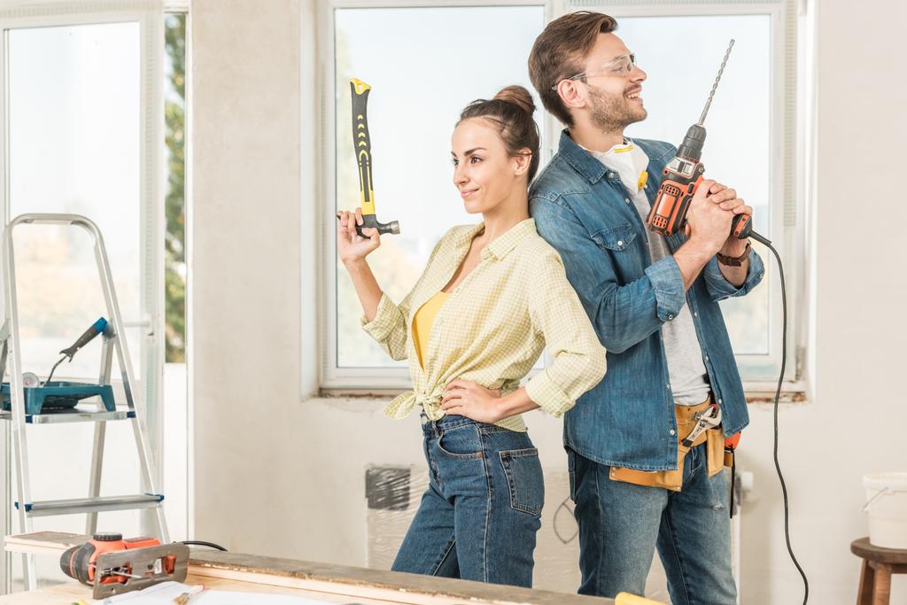 onnellinen nuori pari tilalla työkaluja ja seisoo takaisin remontin aikana
 - Valokuva, kuva