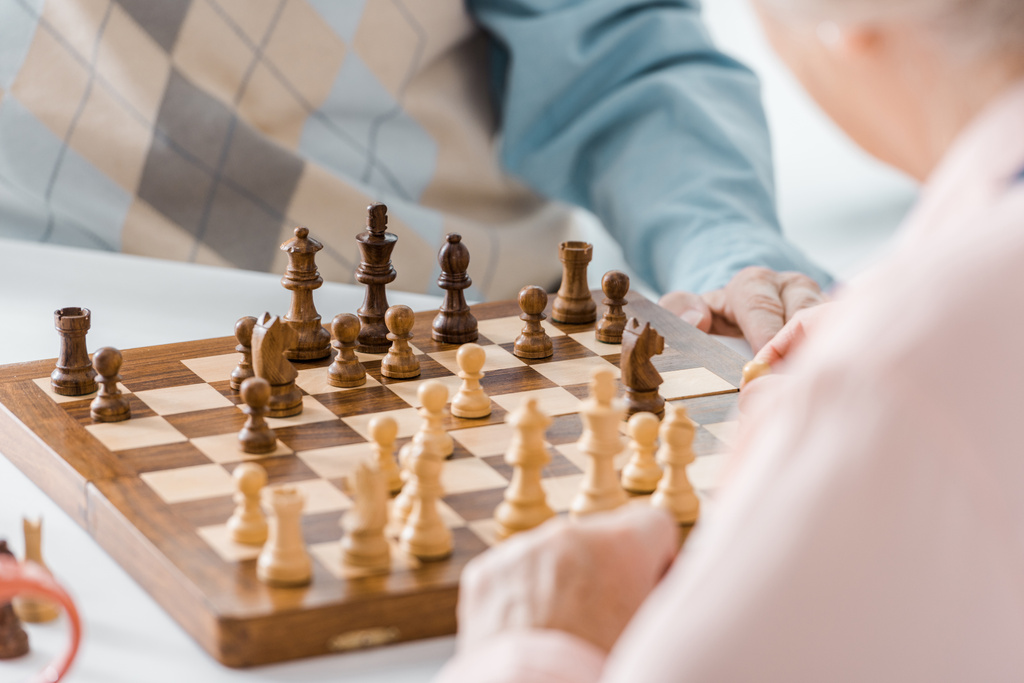 крупным планом пожилая пара играет в шахматы вместе
 - Фото, изображение