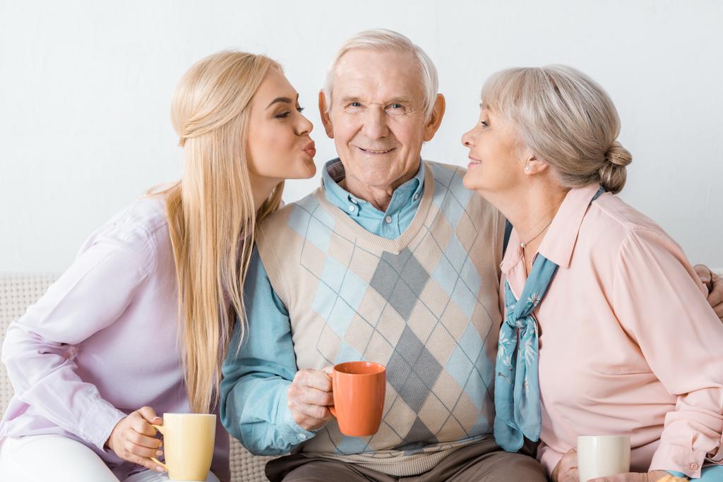 csók boldog magas rangú ember, fiatal és idős nők - Fotó, kép