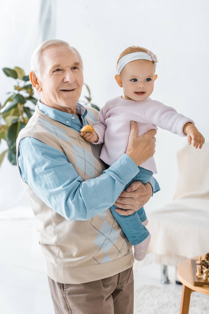 старший дедушка держит внучку с печеньем
 - Фото, изображение