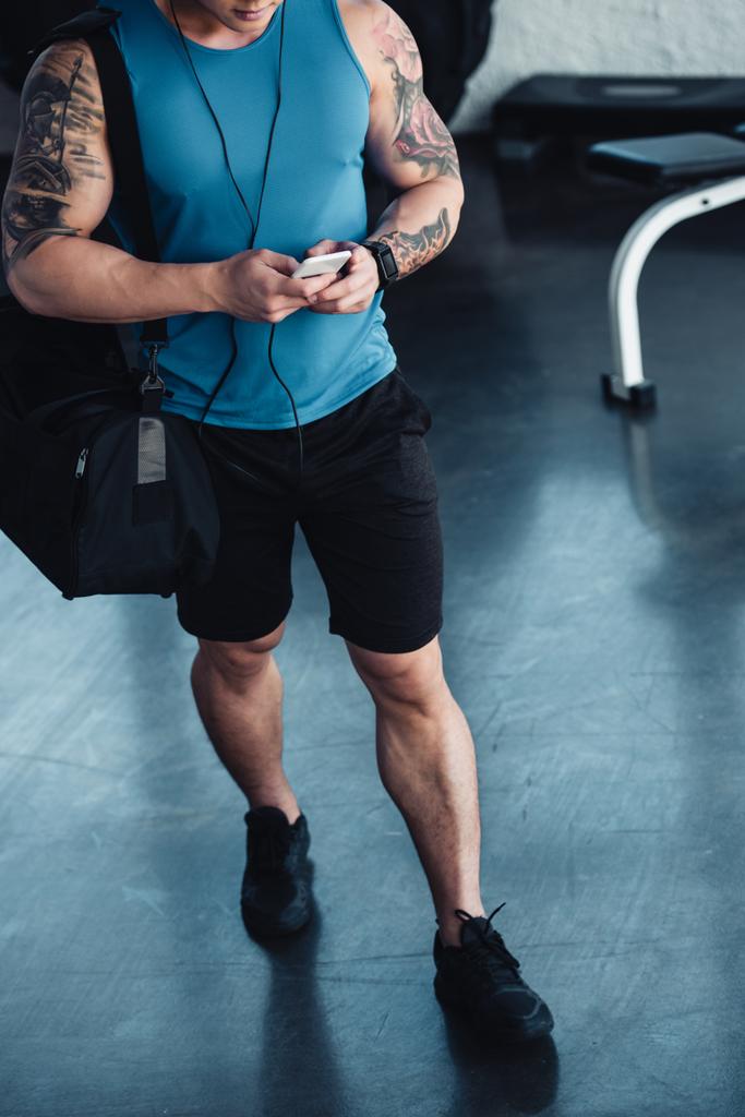 vue recadrée d'un jeune sportif utilisant un smartphone dans une salle de gym
 - Photo, image