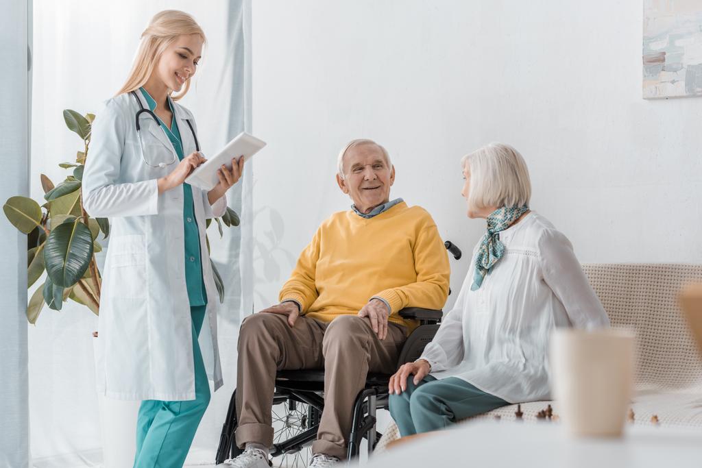 νεαρός χαμογελαστό γυναίκα γιατρός εξετάζει ηλικιωμένους στο Γηροκομείο - Φωτογραφία, εικόνα