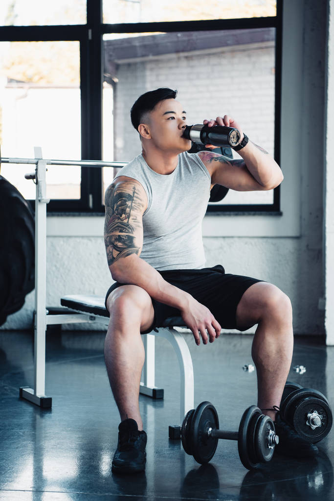 joven asiático deportista beber agua en gimnasio
  - Foto, imagen
