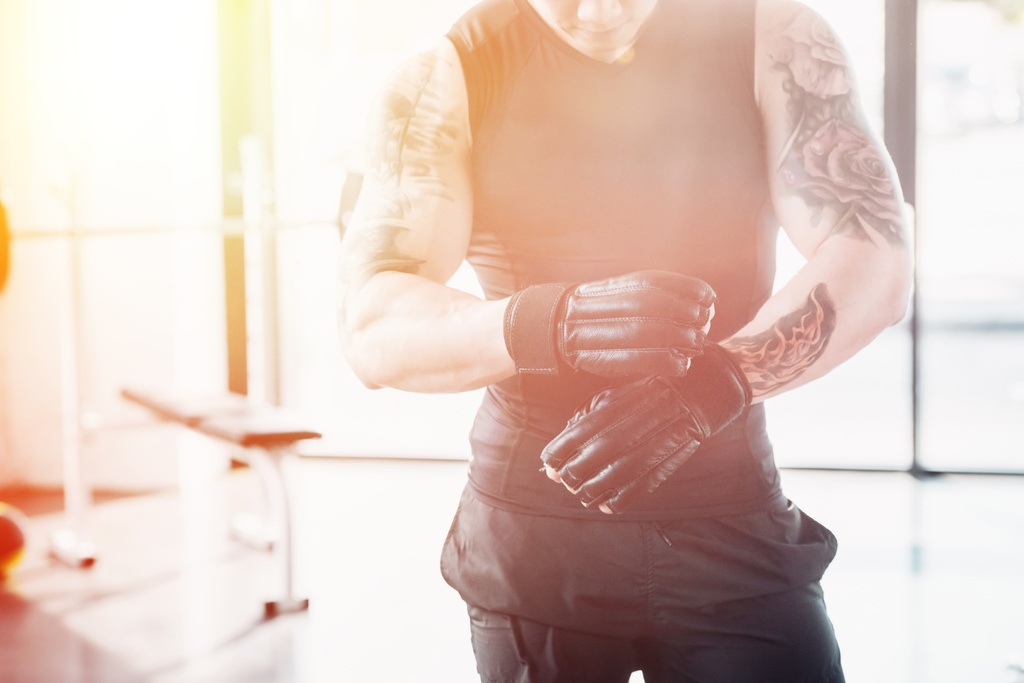 Ausgeschnittene Ansicht eines jungen Sportlers mit Boxhandschuhen im Sonnenlicht - Foto, Bild
