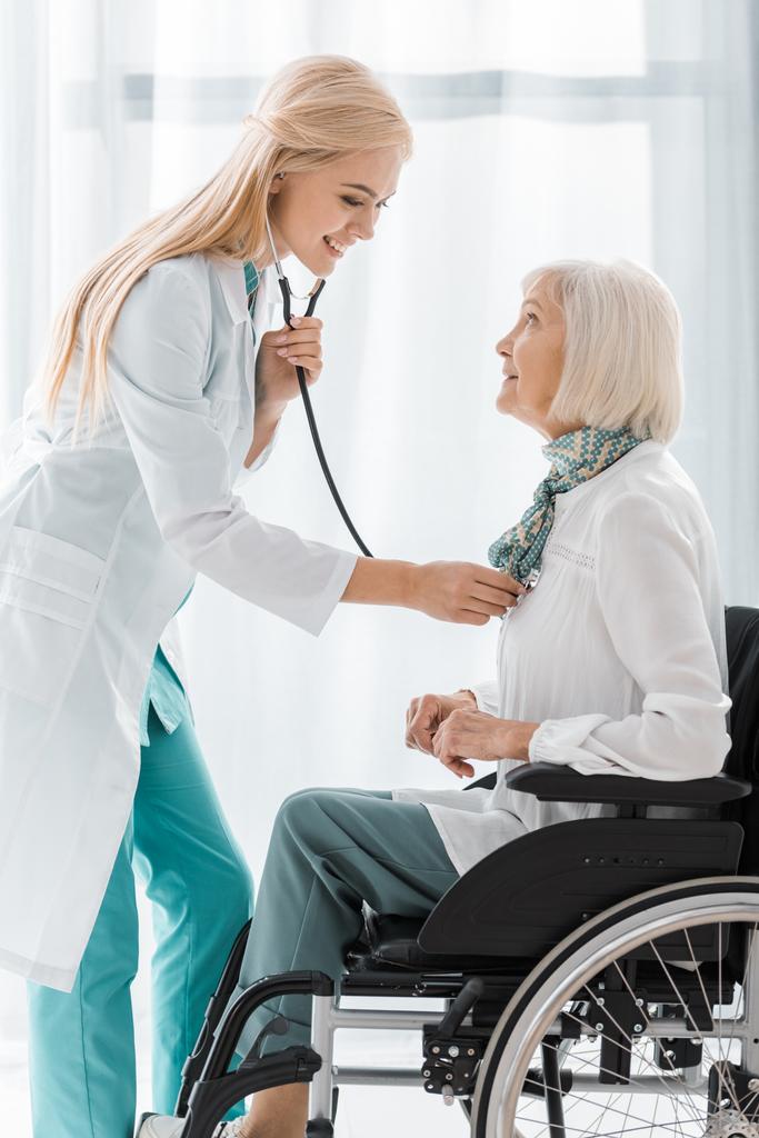 jeune femme médecin examinant avec stéthoscope femme âgée handicapée
  - Photo, image