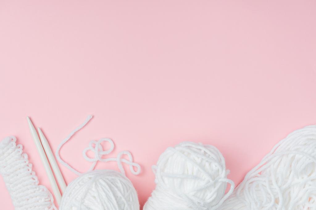 επίπεδη lay με άσπρα νήματα και βελόνες πλεξίματος σε ροζ φόντο - Φωτογραφία, εικόνα