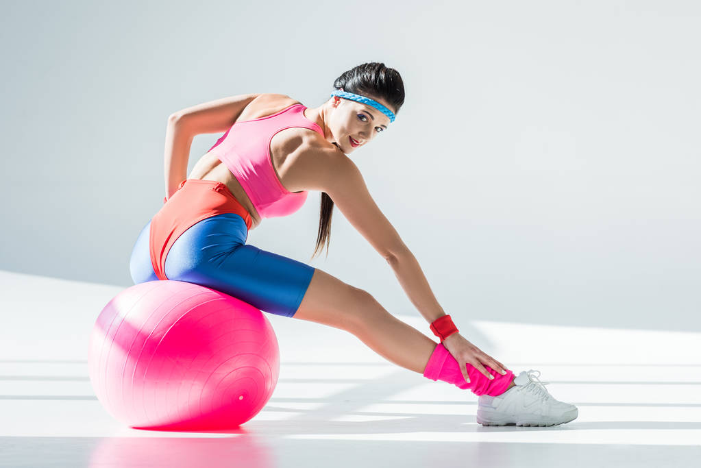 όμορφο αθλητικό κορίτσι συνεδρίαση και την άσκηση στο γυμναστήριο μπάλα σε γκρι - Φωτογραφία, εικόνα