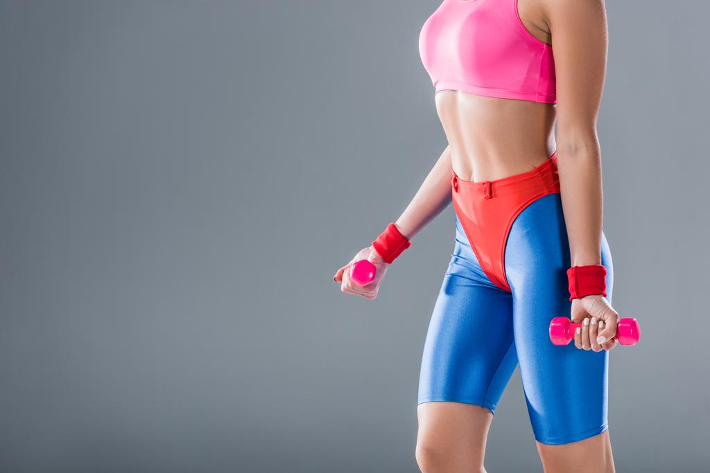 обрезанный снимок спортивной девушки, тренирующейся с гантелями, изолированными на сером
 - Фото, изображение