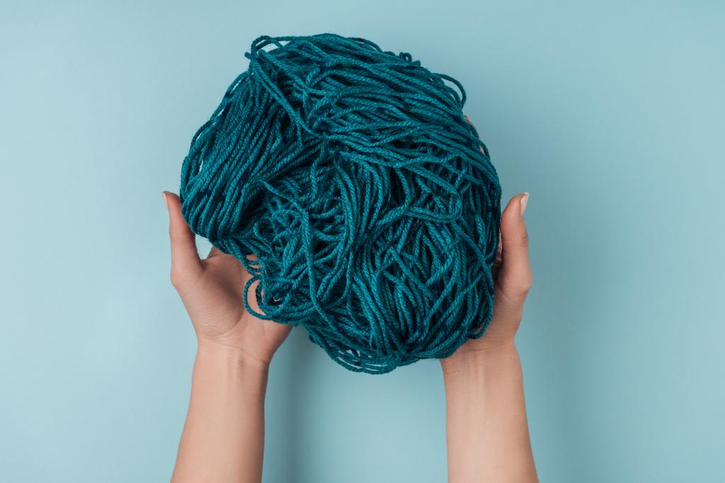 vue partielle de la femme tenant du fil pour tricoter dans les mains sur fond bleu
 - Photo, image