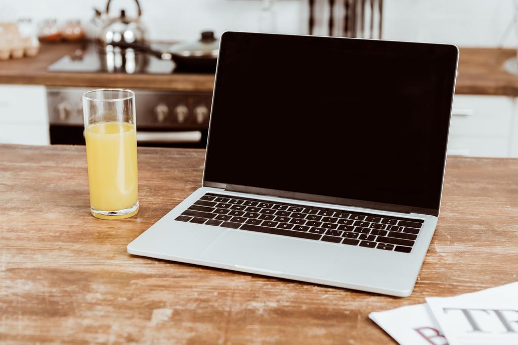 Selektivní fokus laptop s prázdnou obrazovkou a pomerančová šťáva u stolu  - Fotografie, Obrázek