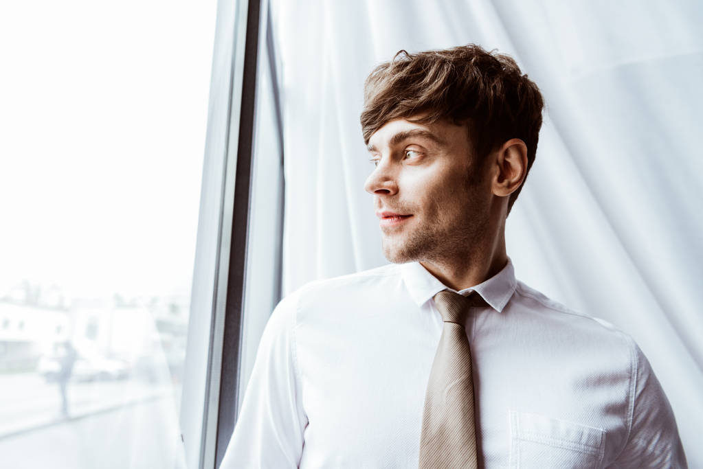 портрет бизнесмена в белой рубашке и галстуке, смотрящего в сторону в офисе
 - Фото, изображение