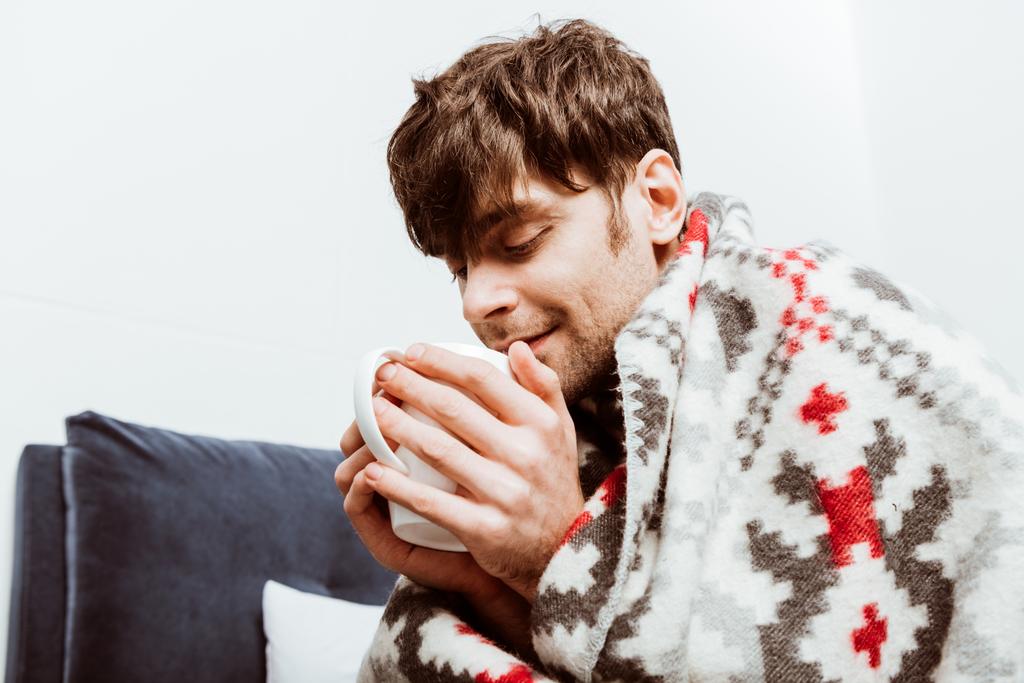 Kranker Mann in Decke gehüllt trinkt zu Hause Tee im Bett  - Foto, Bild