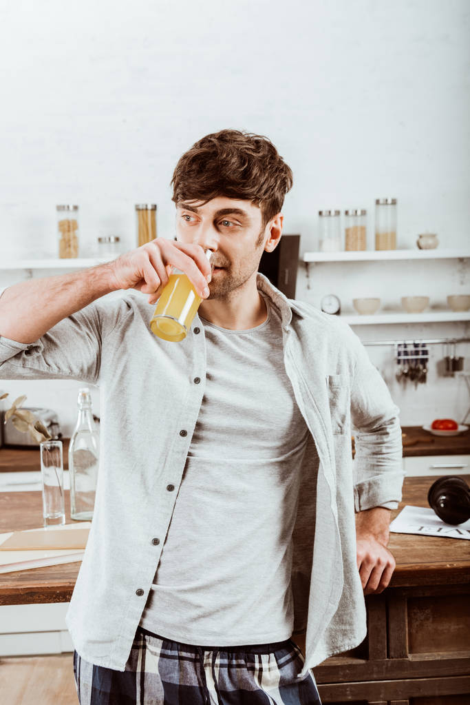 muž pít pomerančový džus na snídani v kuchyni doma - Fotografie, Obrázek