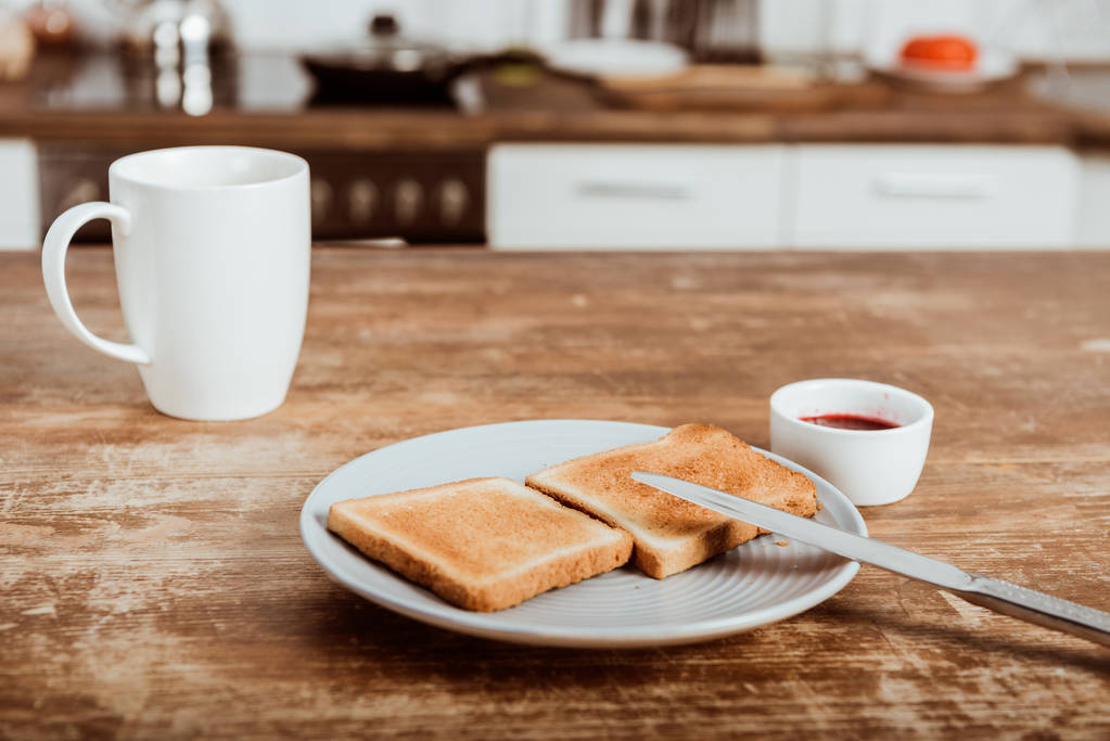 focalizzazione selettiva di pani tostati su piatto, marmellata e tazza di caffè a tavola in cucina
  - Foto, immagini