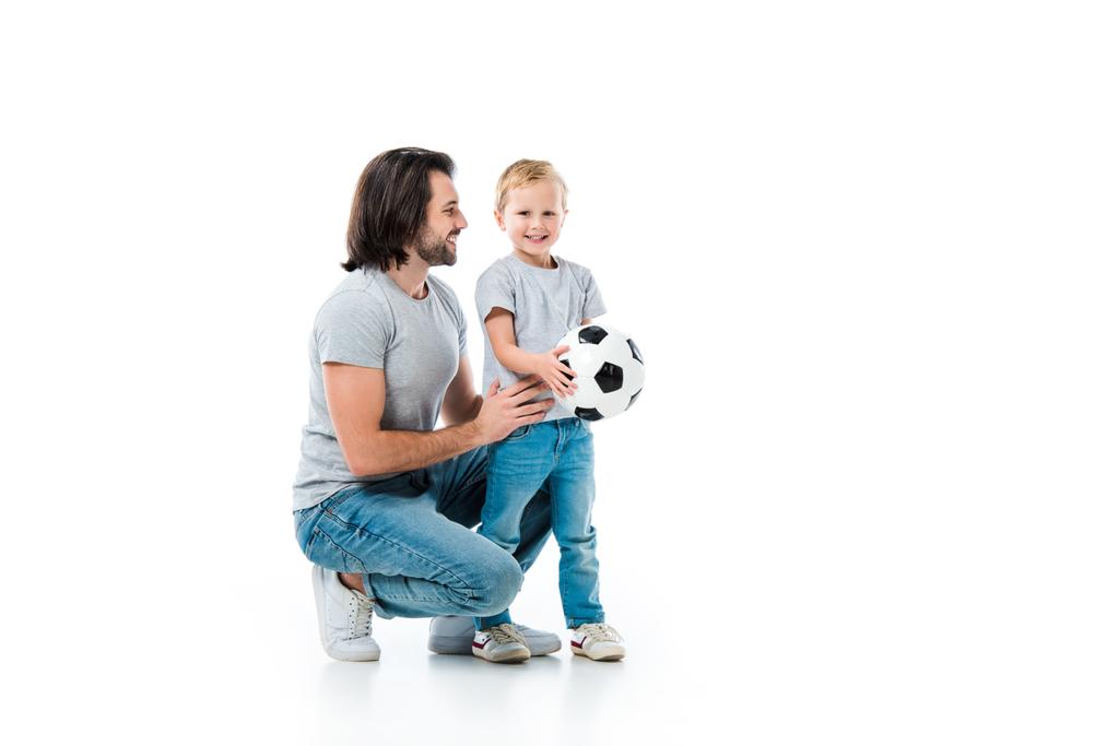 Pai abraçando e olhando para seu filho feliz com bola de futebol isolado no branco
 - Foto, Imagem