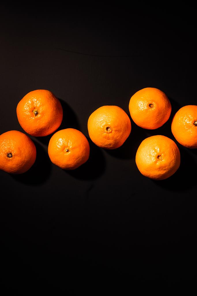 top view of arrangement of wholesome tangerines on black background - Photo, Image