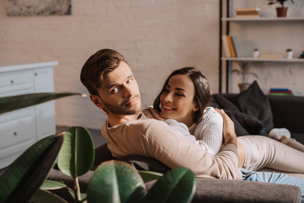 счастливая романтическая молодая пара флиртует дома на диване
 - Фото, изображение