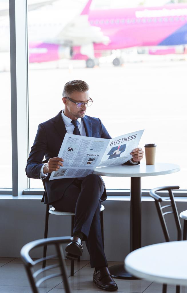 dla dorosłych przystojny biznesmen czytanie gazety w kawiarni na lotnisku - Zdjęcie, obraz