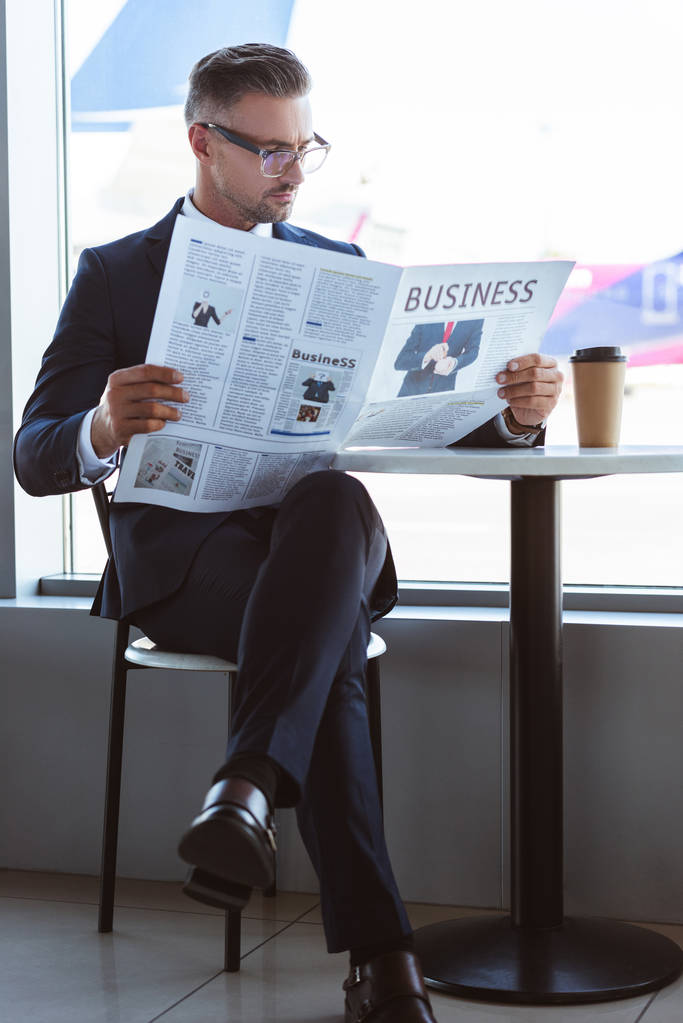 volwassen zakenman lezen van de krant in café op luchthaven - Foto, afbeelding
