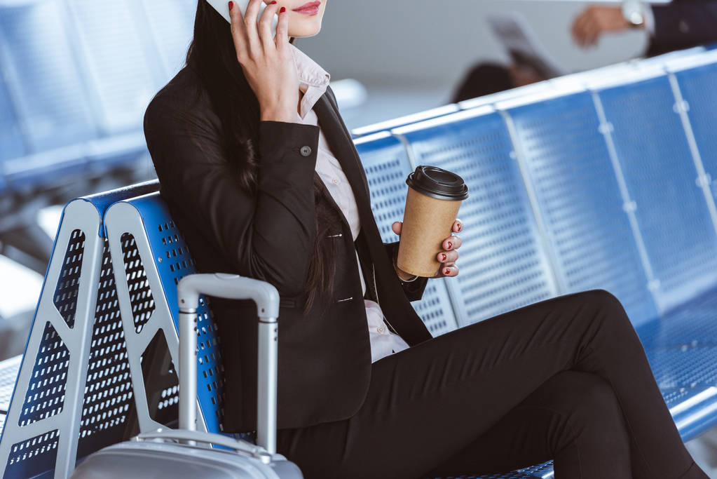 zbliżenie na młoda kobieta interesu w okularach z bagażu za pomocą smartfona na lotnisko - Zdjęcie, obraz