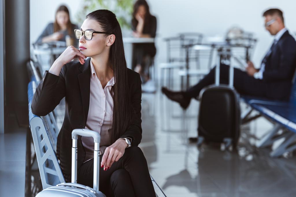 Erwachsene Geschäftsfrau sitzt in Abflughalle am Flughafen - Foto, Bild