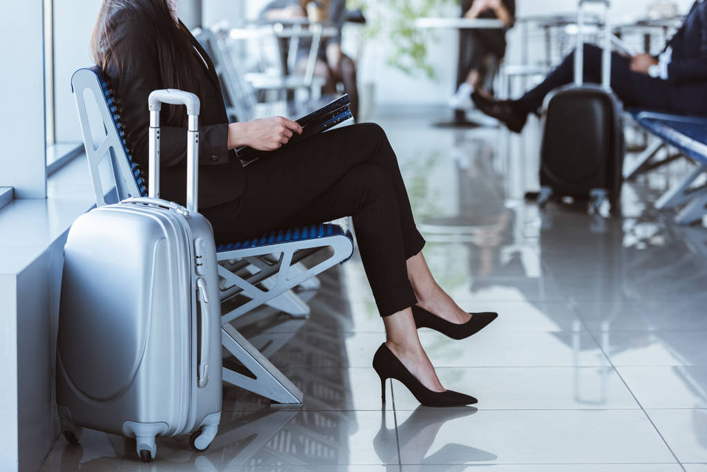 Geschäftsfrau mit schwarzem Ordner sitzt in Abflughalle am Flughafen - Foto, Bild