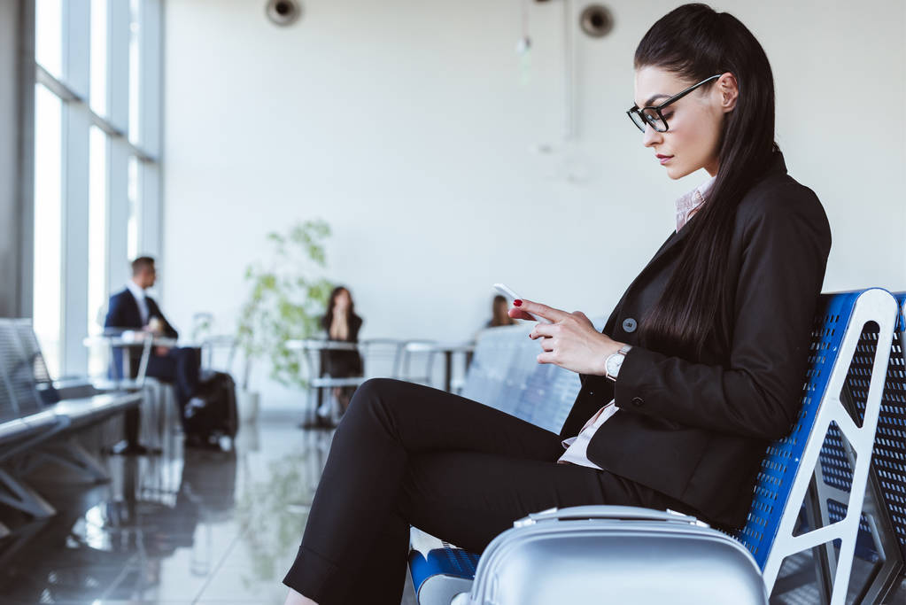 junge Geschäftsfrau mit Smartphone in Abflughalle am Flughafen - Foto, Bild