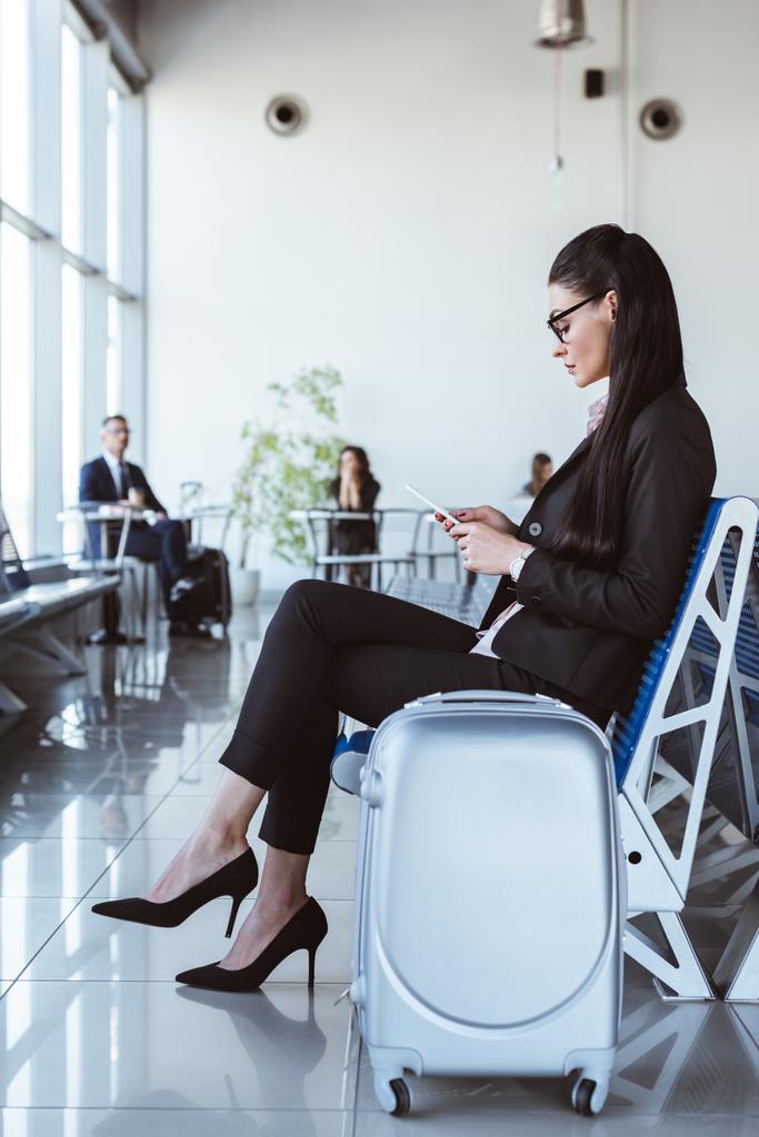 giovane donna d'affari in occhiali con smartphone seduta alla sala partenze in aeroporto
 - Foto, immagini