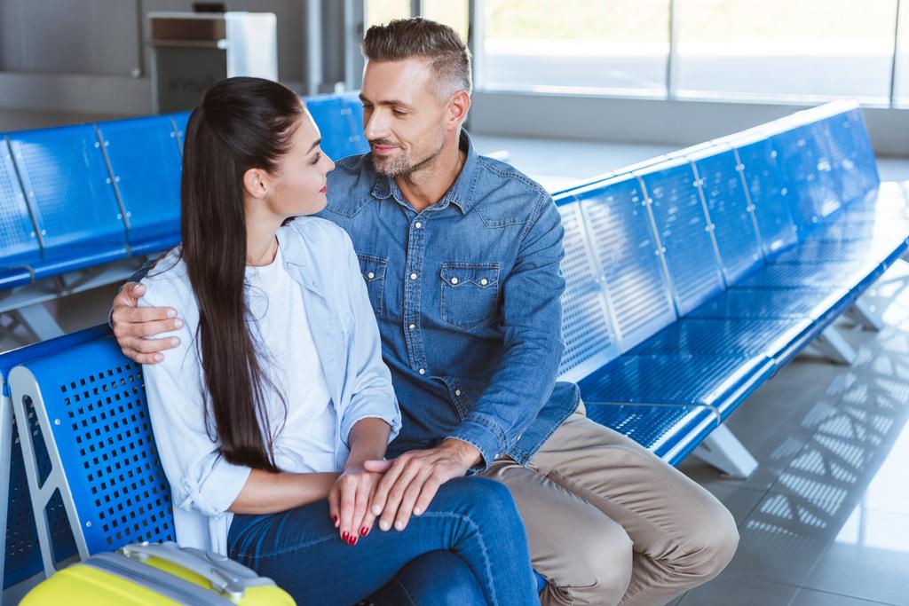 Мужчина обнимает и смотрит на свою прекрасную девушку в аэропорту
 - Фото, изображение