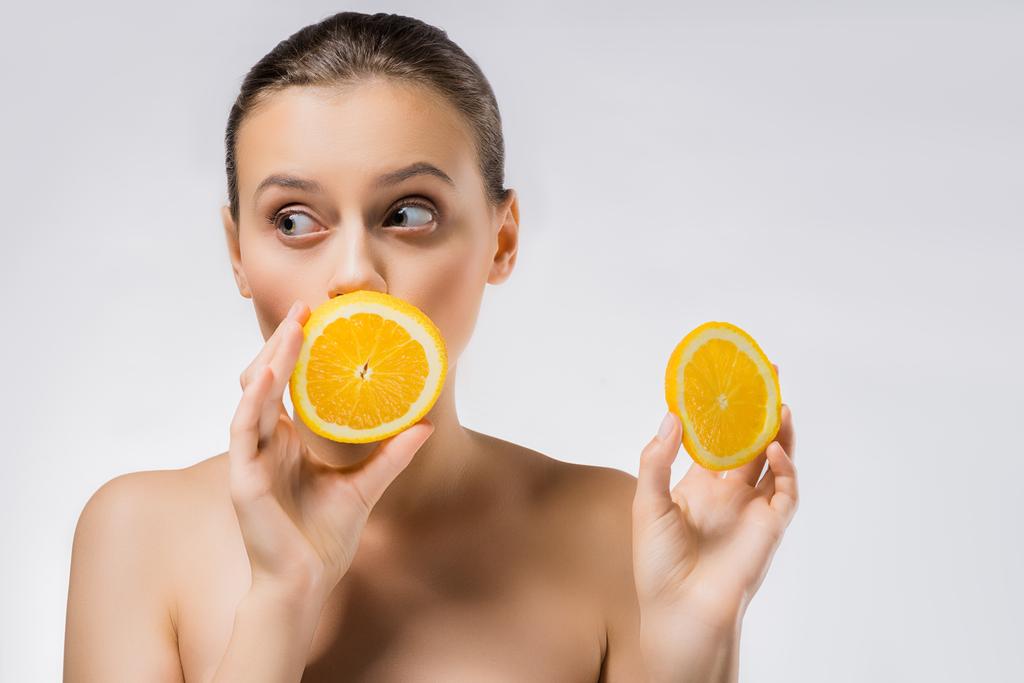 mujer joven con expresión de la cara divertida y rodajas de naranja
 - Foto, Imagen
