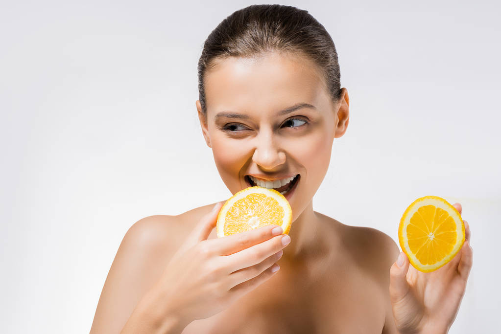 mujer joven sosteniendo y mordiendo rebanada de naranja
  - Foto, Imagen