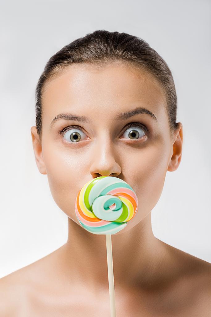 fiatal, vonzó nő bujkál a szája mögött színes nyalóka - Fotó, kép