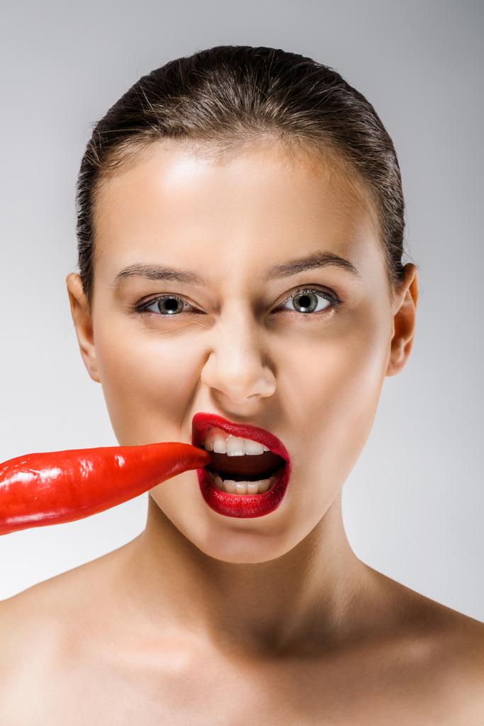 young beautiful woman with red lips biting chili pepper - Photo, Image
