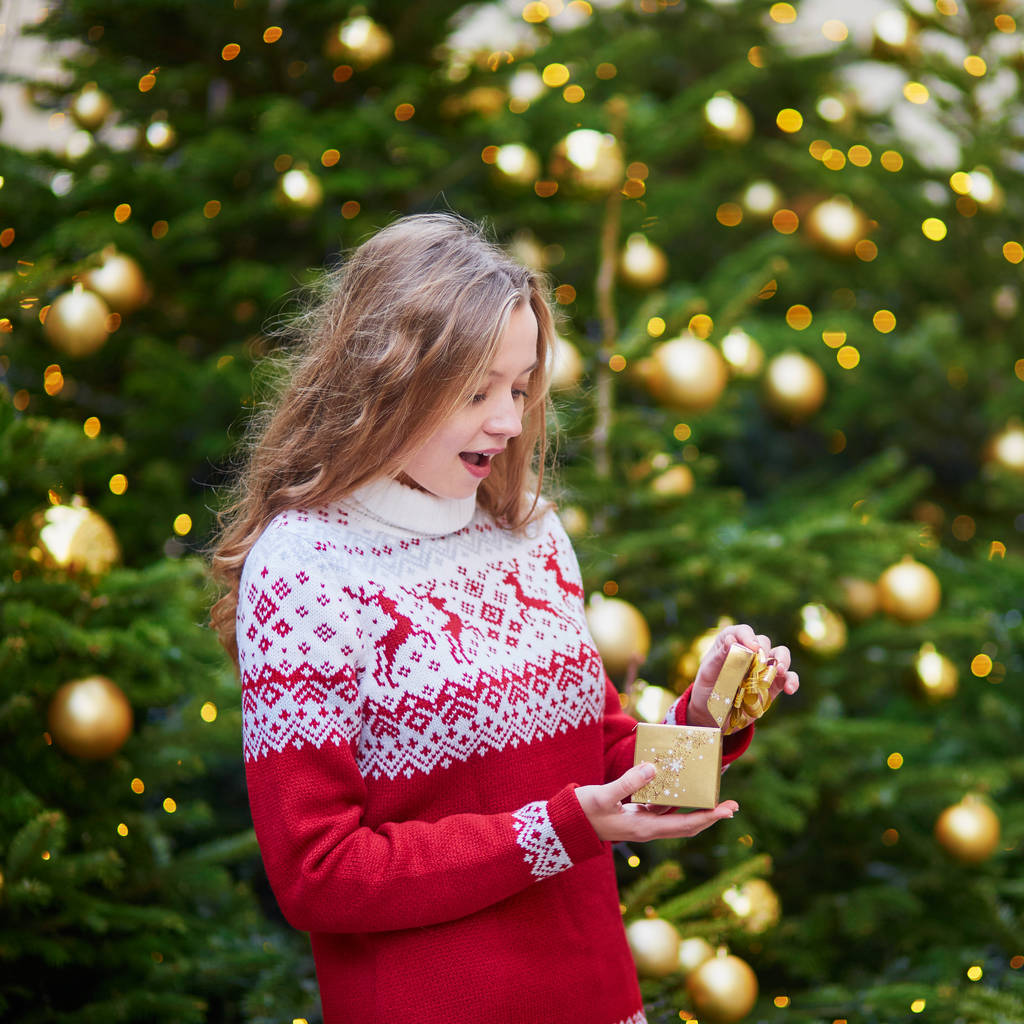 Menina alegre com presente de Natal perto da árvore de Natal decorada
 - Foto, Imagem
