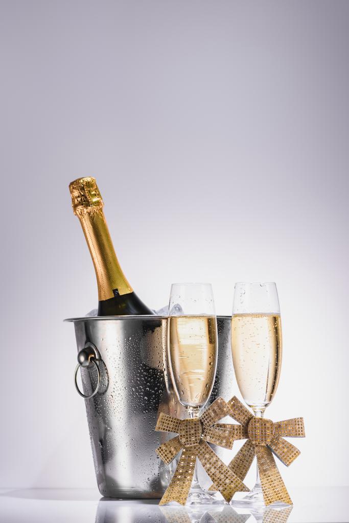 close up view of bottle of champagne in bucket and glasses of champagne on grey backdrop - Photo, Image
