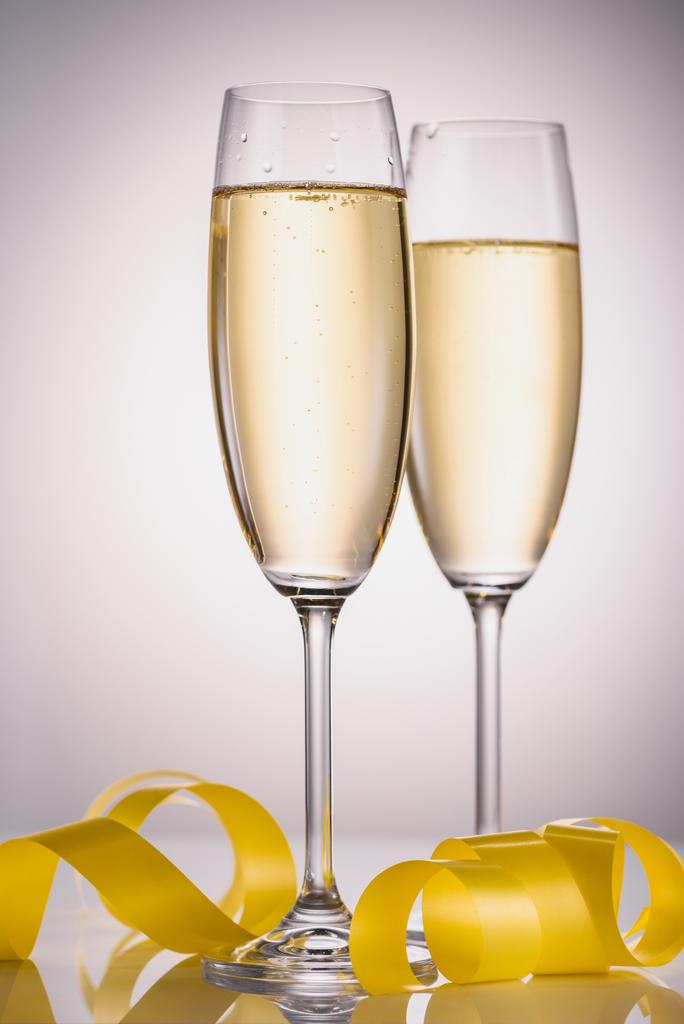 vue rapprochée des verres de champagne et confettis festifs jaunes sur fond gris
 - Photo, image