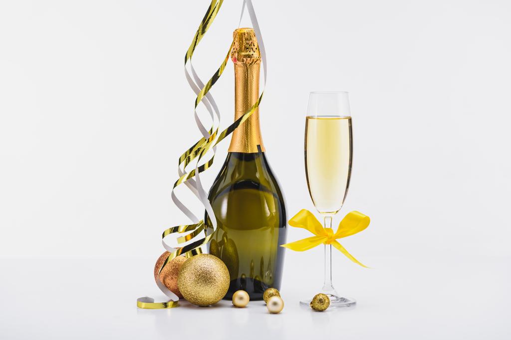 закрыть вид на бутылку и бокал шампанского, конфетти и рождественские игрушки на белом фоне
  - Фото, изображение