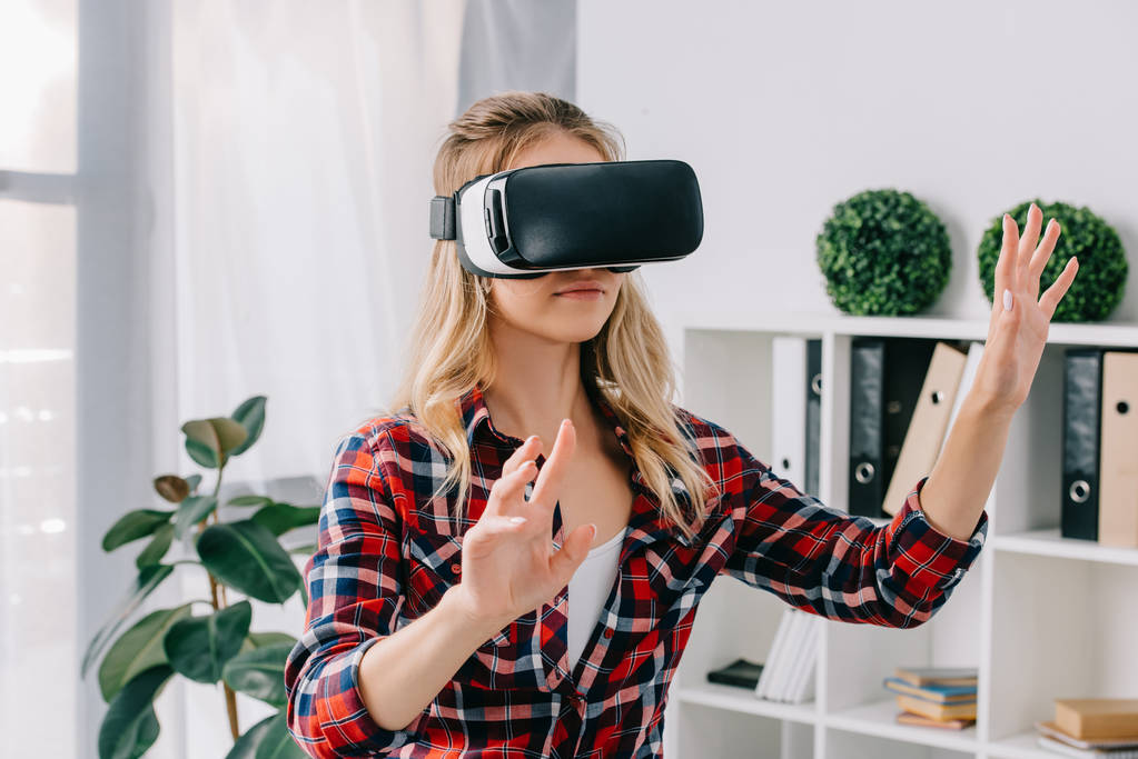 young woman in virtual reality headset gesturing in room - Photo, Image