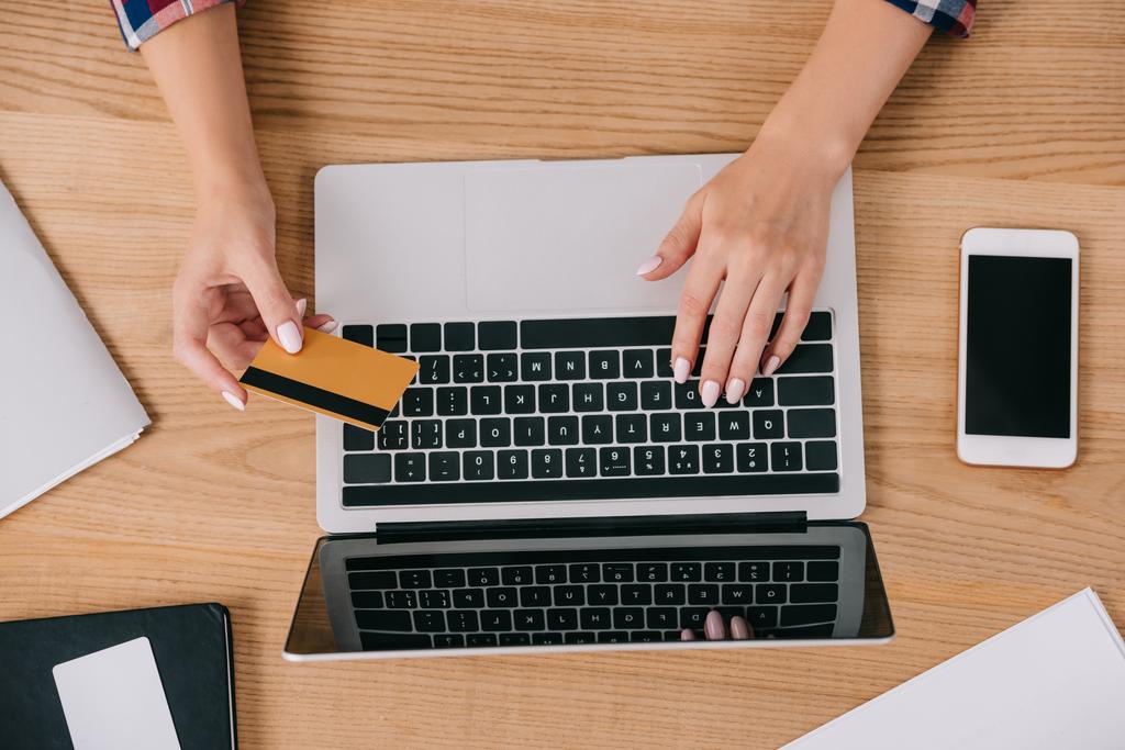 visão parcial da mulher com cartão de crédito fazendo compra on-line na mesa de madeira
 - Foto, Imagem